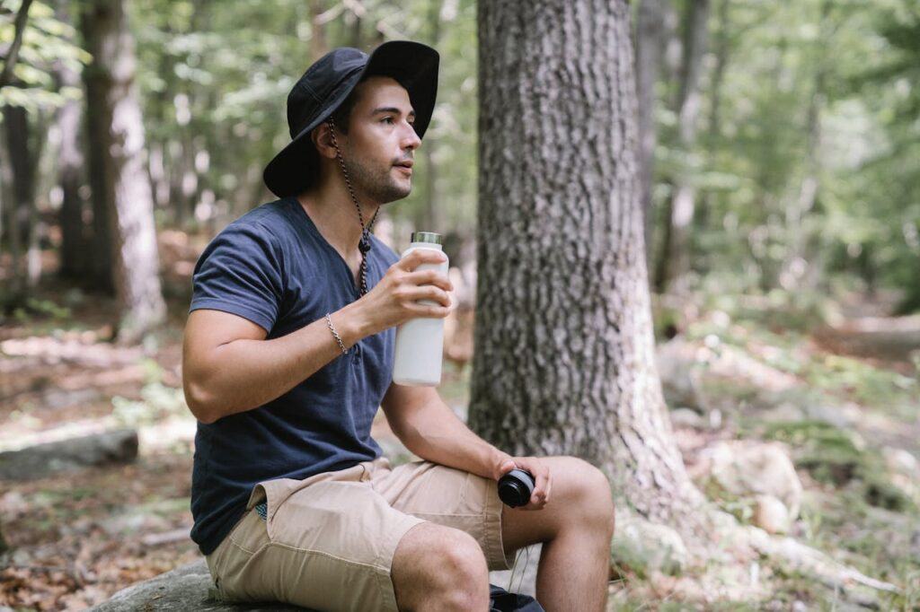 Hiker wearing a hydration pack and sipping water during a sunny summer hike